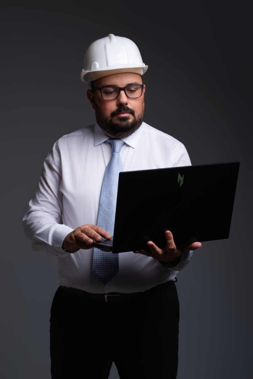 Gustavo Santos usando capacete de engenharia e segurando notebook
