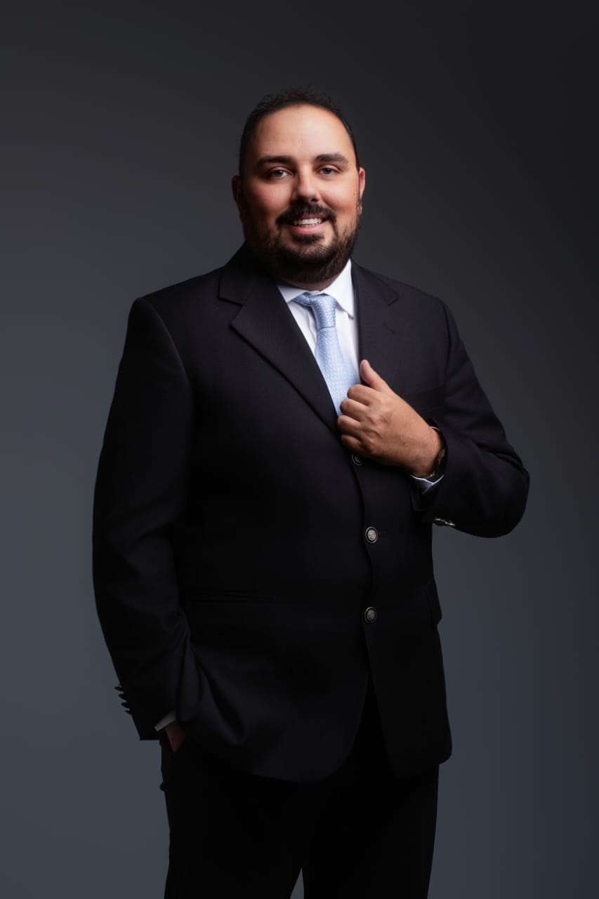 Gustavo Santos em retrato profissional, sorrindo em ambiente executivo