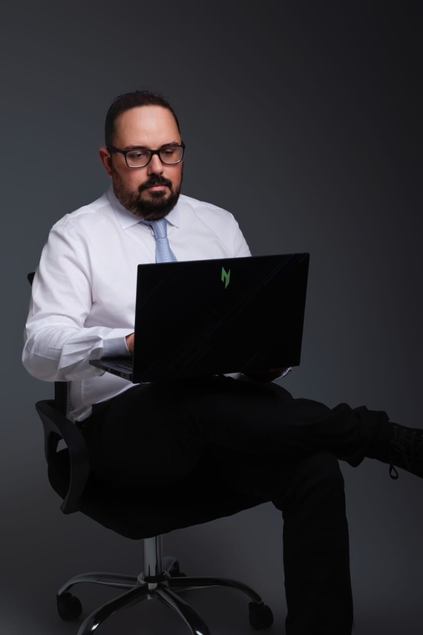 Gustavo Santos sentado com notebook em ambiente profissional